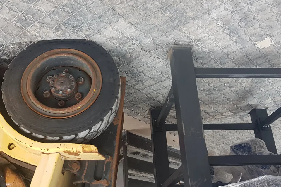 Roda de uma empilhadeira parada sobre as placas de proteção, ao lado de uma estrutura metálica