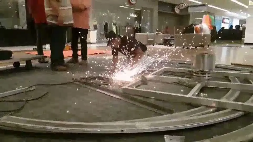Operário cortando estrutura metálica com esmerilhadeira, com faíscas caindo sobre o piso protegido