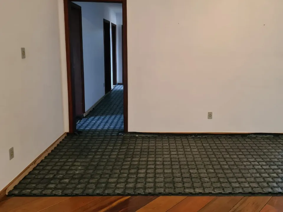 Ambiente com piso de madeira protegido pelas placas até o rodapé, com portas abertas para outros cômodos