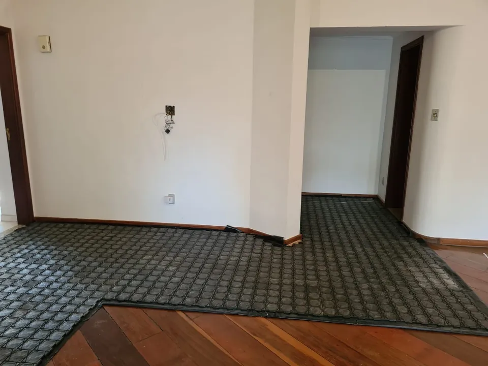 Sala com piso de tábua corrida coberto pelas placas, que contornam o recorte da parede e deixam a madeira aparecendo na borda