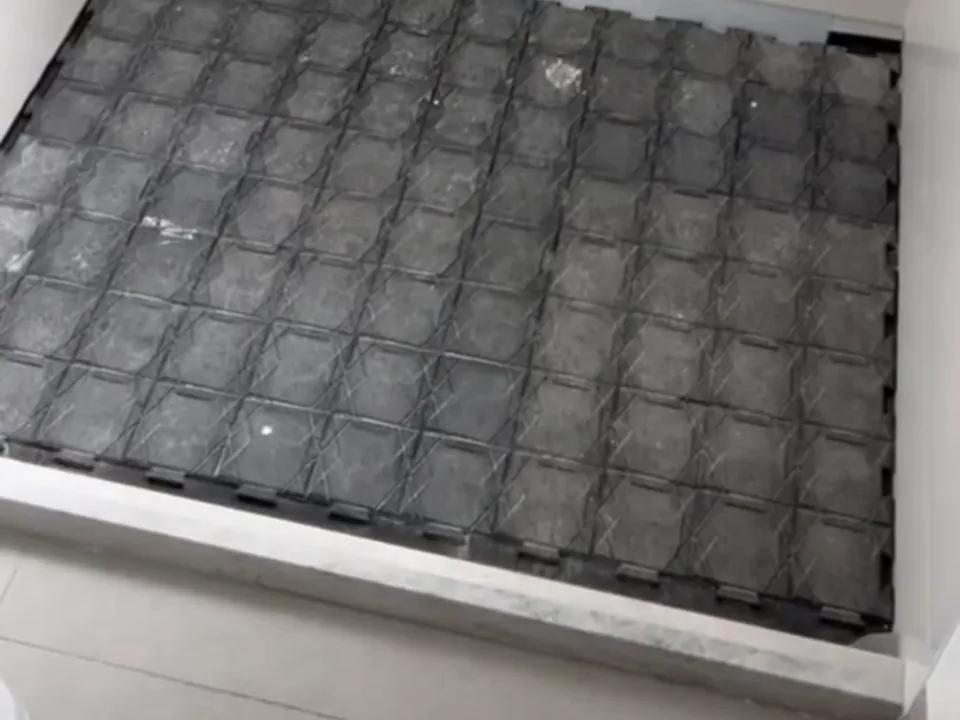 Placas de proteção encaixadas no piso de um banheiro revestido de porcelanato claro