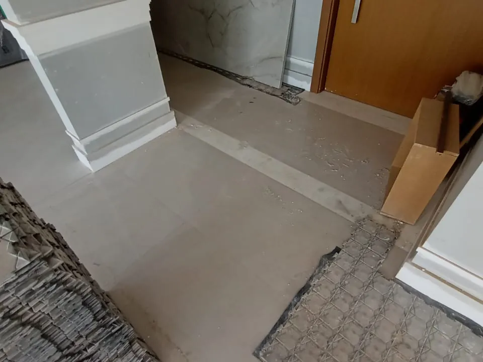Borda das placas de proteção sobre o porcelanato, junto ao rodapé e a um batente de porta