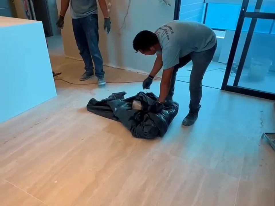Equipe recolhendo a lona no fim da obra, com o porcelanato de grande formato à mostra